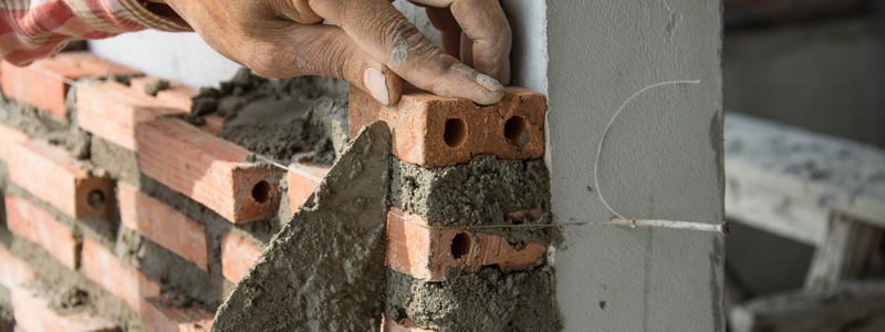 masonry worker with brick and concrete mortar